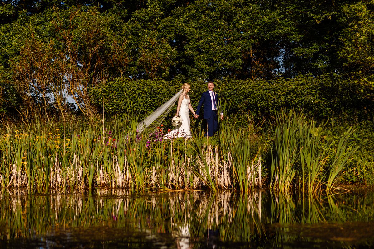 Bride and Groom walking next to the pond at Stanley House Wedding Photography Venue 